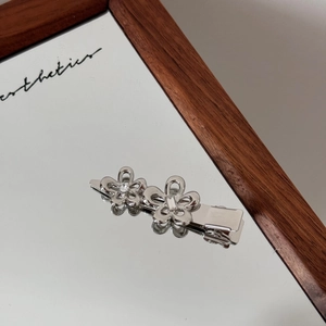 Nahaufnahme einer silbernen Blumen-Haarklammer mit Strasssteinen auf einer Spiegelfläche