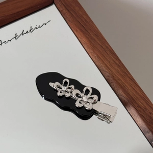 Detail einer silbernen Metall-Blumen-Haarspange mit Strass und schwarzer Basis