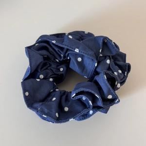 Detail showing deep blue fabric hair scrunchie with white polka dots and texture