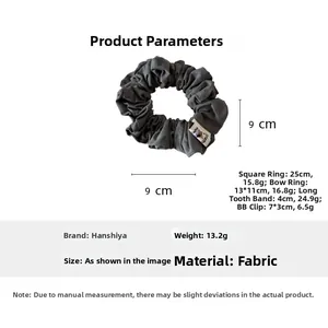 Détail d'un chouchou en tissu gris foncé montrant le diamètre 9cm et le logo