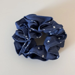 Detailed view of dark blue scrunchie with white heart print and fine striped texture