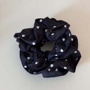 Detail of black fabric scrunchie with white heart pattern and soft pleated texture