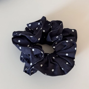 Close-up of black scrunchie with white polka dots featuring high-elastic fabric texture