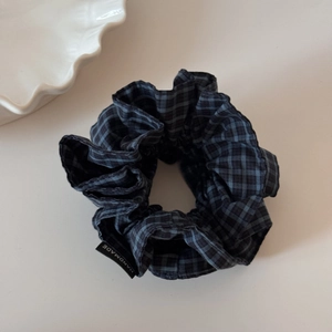 Detail eines blau-schwarz karierten Haargummis mit handgefertigtem Webetikett aus Stoff