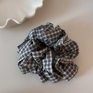 Detail eines großen schwarz-weiß karierten Scrunchies mit kleinem Handmade-Webetikett