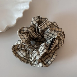 Details eines handgefertigten Haargummis mit schwarz-weißem Karomuster und Label