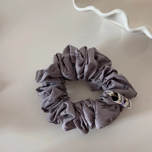 Détail d'un chouchou français gris-violet avec motif de feuilles et étiquette en tissu