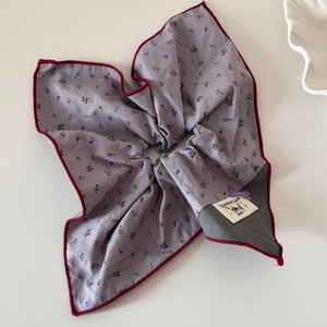 Vue détaillée du chouchou en tissu floral violet avec bordure rouge et étiquette tissée