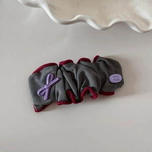 Détail d'un chouchou en tissu gris avec nœud lavande et étiquette Hand made