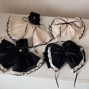 Macro view of beige and black chiffon hair ties with delicate lace edges and heart charms
