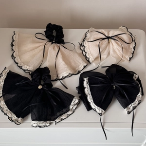Detailed close-up of beige and black lace scrunchies with elegant silk ribbon bows