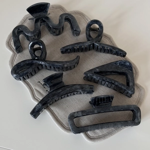 Set of six grey marble texture hair claws in various geometric shapes on a beige mat