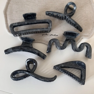 Flat lay of six large grey marble pattern hair claws in various geometric shapes