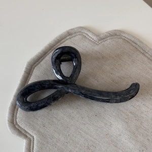 Detail of grey marble resin hair claw clip with metallic spring on linen background