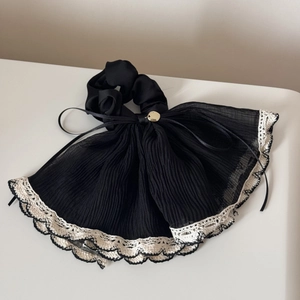 Close-up of black pleated chiffon hair scrunchie with beige lace edges and gold detail