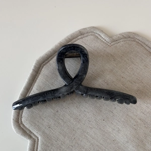 Close-up of a dark grey marble textured claw clip with elegant twist design