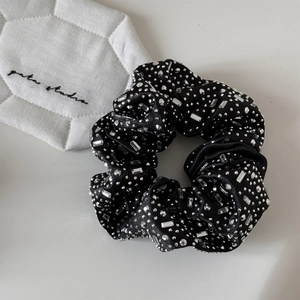 Detailed view of luxury black satin scrunchie with shimmering rhinestones and crystals