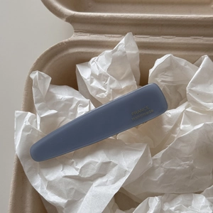 Close-up of blue acetate hair clip with gold France Handmade lettering on paper background