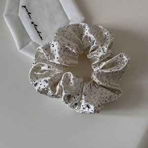 Close-up of cream satin scrunchie featuring heavy rhinestone embellishments and elegant shine