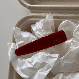 Close-up of deep red acetate hair clip with gold France Handmade logo in a gift box