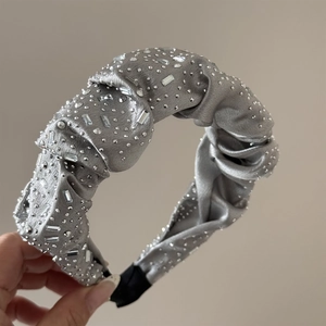 Close-up of grey velvet headband featuring sparkling rhinestones and twisted fabric detail