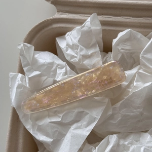 Detailed close-up of acetate duckbill hair clip with marble texture and handmade lettering