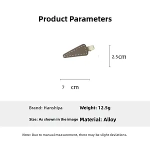 Detail view of a matte gray triangular hair clip with white stitching and 7cm size markings