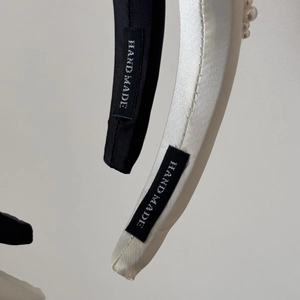 Detailed macro view of handmade satin headbands with pearl accents and quality labeling