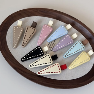 Macro detail of triangle hair clips featuring unique stitch texture in pastel colors