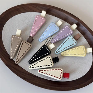 Detail of matte geometric triangle hair clips in assorted candy colors with stitch texture