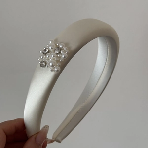 Detail of cream white satin headband featuring elegant pearls and sparkling rhinestones