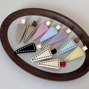 Detailed close-up of 10-piece triangle hair clips with contrast stitching on wooden tray