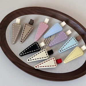Macro detail of matte triangle hair clips in multiple candy colors on a wooden tray