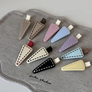 Close-up of colorful triangle hair clips with stitch detail on grey linen surface