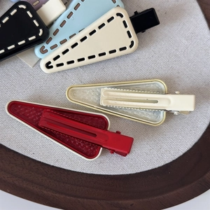 Macro detail of matte and grid texture triangular hair clips in assorted colors