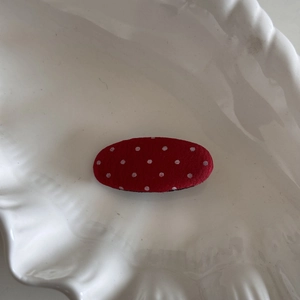 Vue détaillée d'une barrette en tissu rouge à pois blancs sur un plateau coquillage