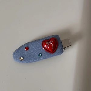 Close-up of denim blue heart hair clip with red peach heart and sparkling small rhinestones
