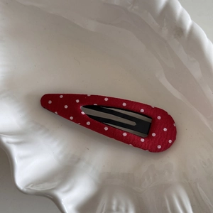 Gros plan détaillé d'une barrette à cheveux rouge à pois blancs sur un plateau blanc