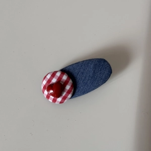 Detailed shot of a denim blue hair clip featuring a red gingham base and resin heart charm