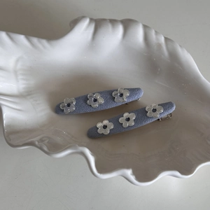 Detail of lavender fabric hair clips with silver hollow heart-shaped floral accents