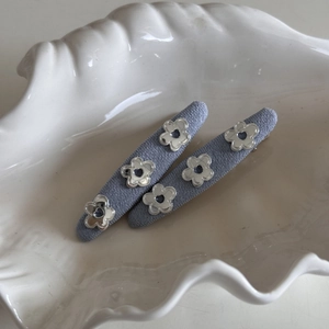 Close-up of two denim fabric hair clips with silver mirror flower and heart cutout details