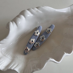 Detail of lavender fabric hair clips with silver metal flowers on a white shell plate