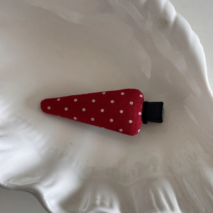 Détail de la pince à cheveux rouge à pois blancs avec base en métal noir de type bec de canard