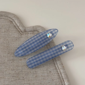 Gros plan de barrettes à carreaux bleus avec strass en forme de cœur sur support tissu