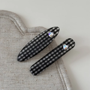 Détail de deux barrettes à damier avec cristaux en forme de cœur sur lin gris élégant