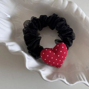 Détail d'un charm cœur à pois rouges sur chouchou en maille noire et plateau coquillage
