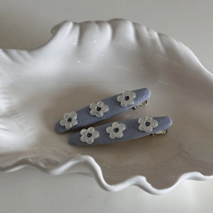 Detailed macro view of two light purple fabric-wrapped hair clips with silver flower charms