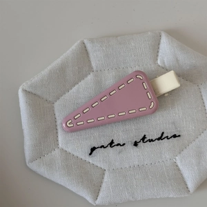 Detailed macro view of purple triangle hair clip with white stitching on quilted fabric