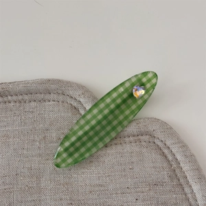 Détail d'une pince à cheveux à carreaux verts avec strass étincelant en forme de cœur