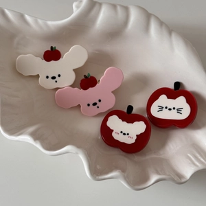 Détail de pinces à cheveux mignonnes en acétate avec motifs de chiot et pomme sur plateau